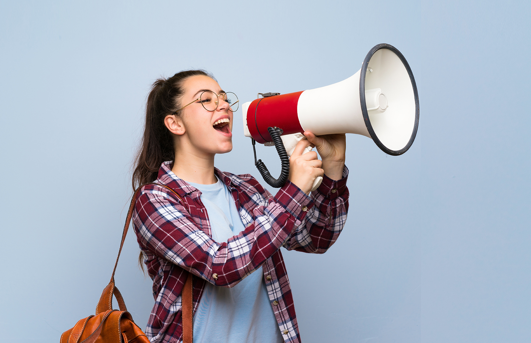 Teenager student girl over isolated blue wall shouting through a megaphone